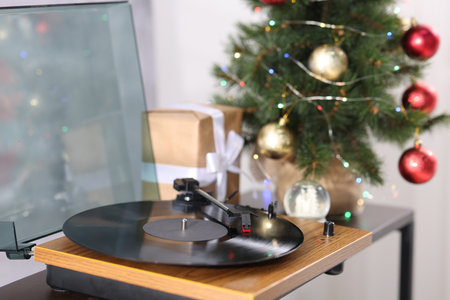 Turntable with vinyl record, gift box and Christmas tree on wooden tableの写真素材