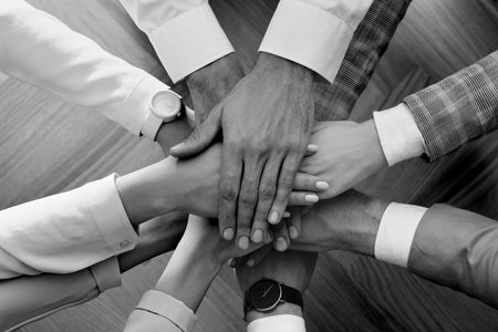 Group of people stacking their hands together, top view. Black-and-white toningの写真素材