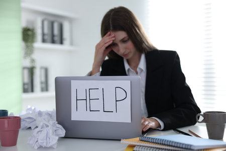 Woman with sign Help on laptop at table in office, selective focus