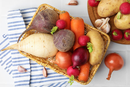 Different raw vegetables on white tiled table, flat lay
