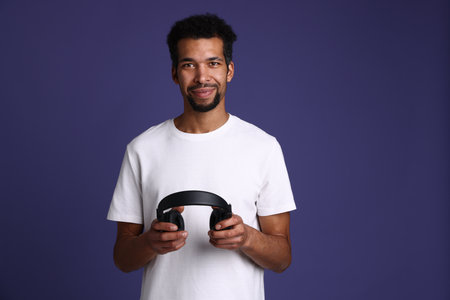 Man with stylish headphones on purple background