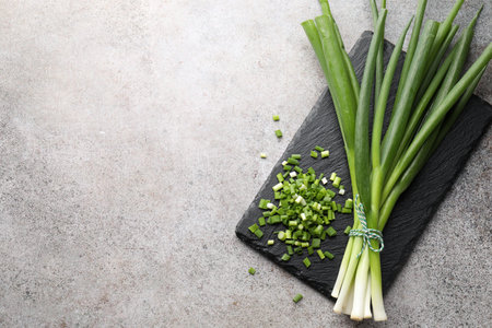 Fresh ripe green onions on light gray table, top view. Space for text