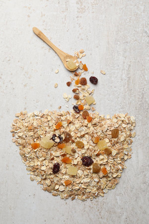 Making granola. Bowl made of oat flakes, dried fruits and nuts and spoon on light gray table, flat layの写真素材