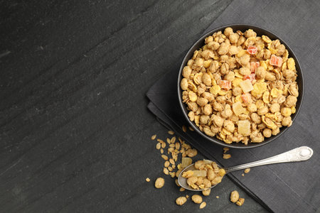 Tasty granola with dried fruits in bowl on black table, flat lay. Space for textの写真素材