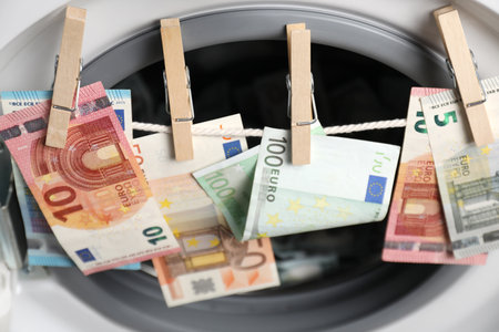 Euro banknotes hanging on string near washing machine, closeup