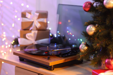 Turntable with vinyl record, gift boxes and Christmas tree on table