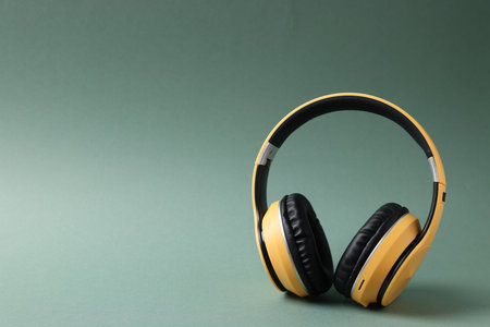 Pair of stylish headphones on pale green background, space for text