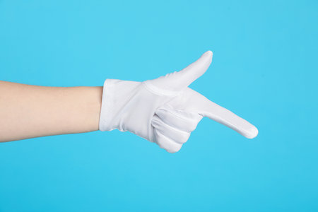 Woman in cloth glove pointing at something on light blue background, closeup