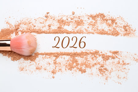 Makeup brush, crushed decorative cosmetic product and numbers 2026 on white background, top view