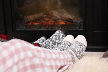 Couple in pajamas near fireplace at home, closeup. Winter season