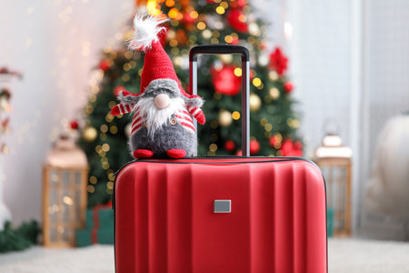Suitcase with decorative dwarf at home against blurred lights, closeup. Christmas vacationの写真素材