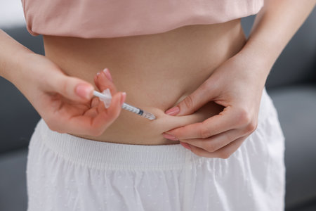 In vitro fertilization. Woman making injection into her belly indoors, closeup