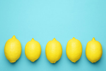 Fresh ripe lemons on light blue background, flat lay. Space for textの写真素材