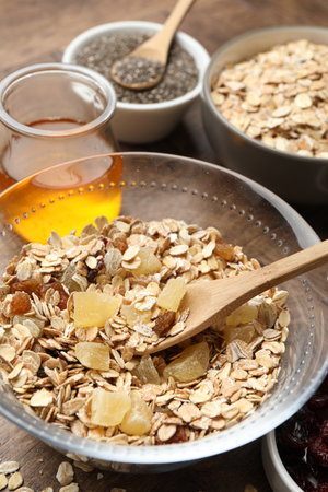 Making granola. Oat flakes with dried fruits in bowl on wooden table, closeup