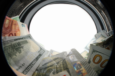 Money in washing machine on white background, view from inside drum