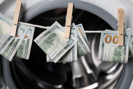 Banknotes hanging on clothesline near washing machine, closeupの写真素材