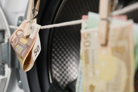 Banknotes hanging on clothesline near washing machine, closeup
