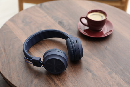 Stylish headphones and coffee on wooden table, closeupの写真素材