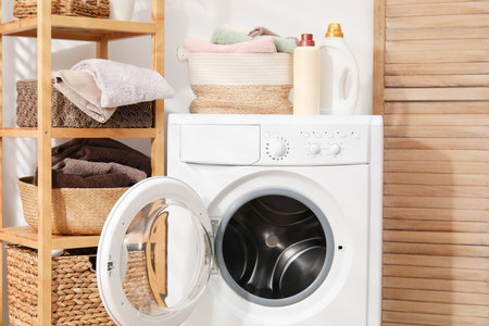 Laundry basket with towels and bottles of detergent on washing machine indoorsの写真素材