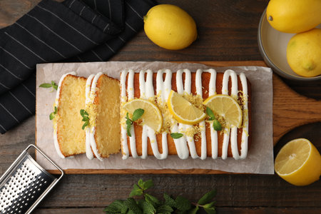 Delicious lemon cake, fresh citrus fruits and grater on wooden table, flat lay