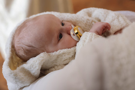 Mother holding her child during baptism ceremony in church, closeup