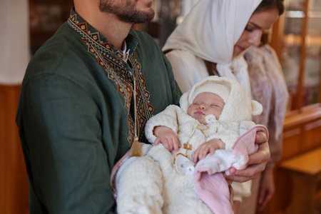 Father holding his child during baptism ceremony in church, closeup
