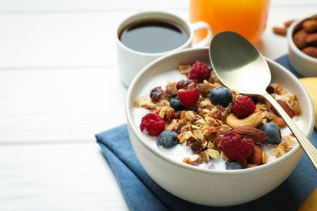 Healthy breakfast. Oatmeal with nuts, berries and milk on white wooden table, closeup. Space for textの写真素材