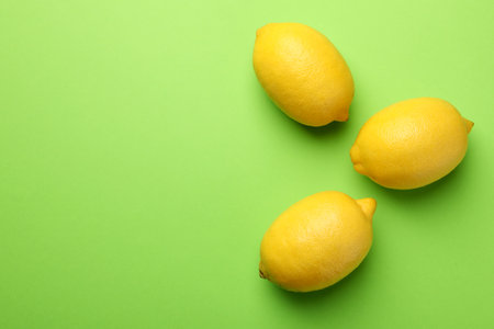 Fresh ripe lemons on light green background, flat lay. Space for textの写真素材