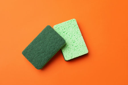 Kitchen sponges on orange background, top view