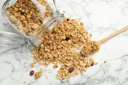 Tasty granola in glass jar on white marble table, top view