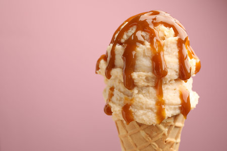 Tasty ice cream with caramel sauce on color background, closeup. Space for textの写真素材
