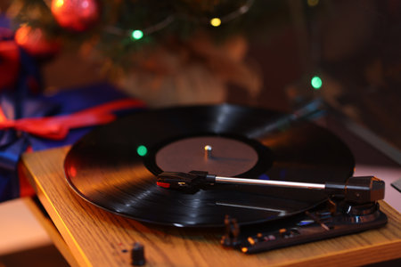 Turntable with vinyl record on table, closeup. Christmas lights reflecting on diskの写真素材