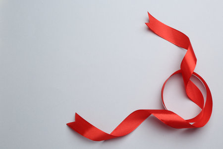 Beautiful red ribbon on light background, top view. Space for textの写真素材