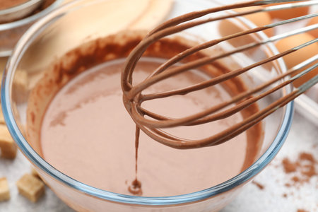 Dripping chocolate dough into bowl at gray table, closeup