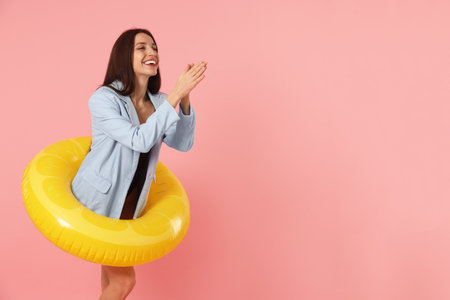 Businesswoman with inflatable ring on pink background, space for textの写真素材
