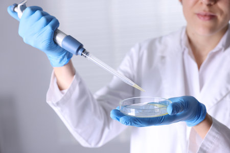 Scientist with dripping motor oil into Petri dish in laboratory, closeupの写真素材