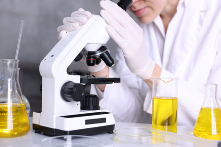Scientist checking motor oil quality at table in laboratory, closeup