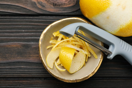 Lemon zest, fresh fruit and peeler on wooden table, flat layの写真素材