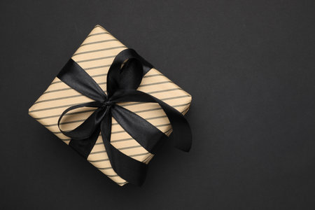 Beautiful wrapped gift box on black background, top view. Space for textの写真素材
