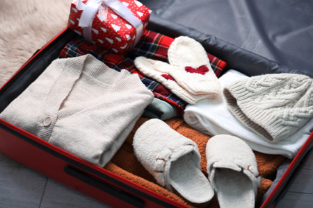 Suitcase with clothes and gift on floor indoors, closeup. Packing for Christmas vacationの写真素材