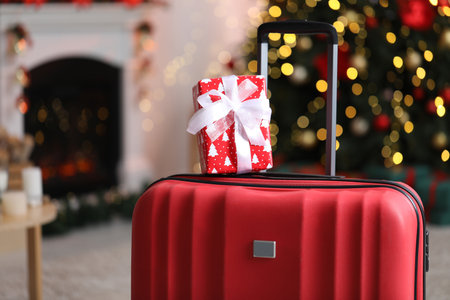 Suitcase with gift at home against blurred lights, closeup. Christmas vacationの写真素材