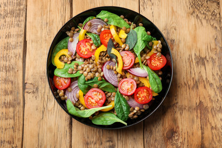 Tasty salad with lentils and vegetables on wooden table, top viewの写真素材
