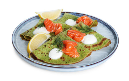 Tasty spinach crepes with salmon, sour cream, dill and lemon isolated on whiteの写真素材