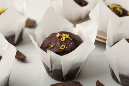 Tasty chocolate muffins with lemon zest on white table, closeupの写真素材