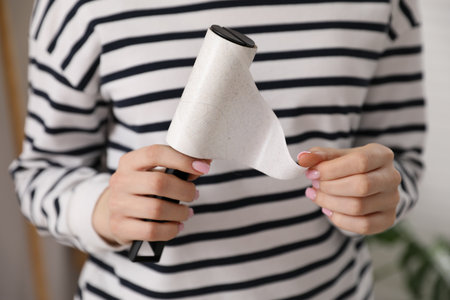 Woman removing sticky tape from lint roller at home, closeupの写真素材