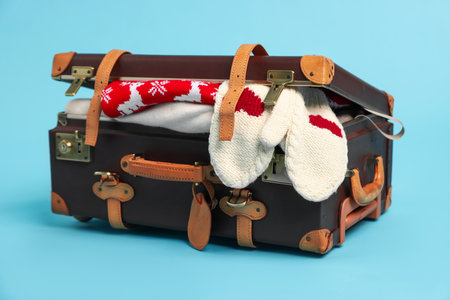 Suitcase with clothes on light blue background. Christmas vacationの写真素材