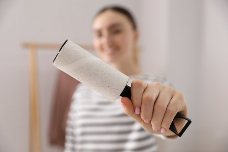 Woman with lint roller at home, selective focusの写真素材