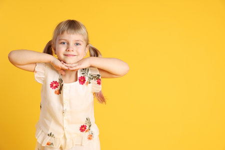 Cute little girl posing on yellow background. Space for textの写真素材