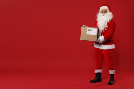 Santa Claus with parcel on red background, space for textの写真素材
