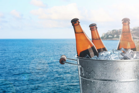 Beer in metal bucket with ice near sea. Refreshing summer drinkの写真素材
